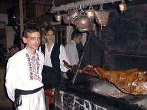 Staff in traditional Bulgarian dress roast a whole lamb slowly over a low wood fire